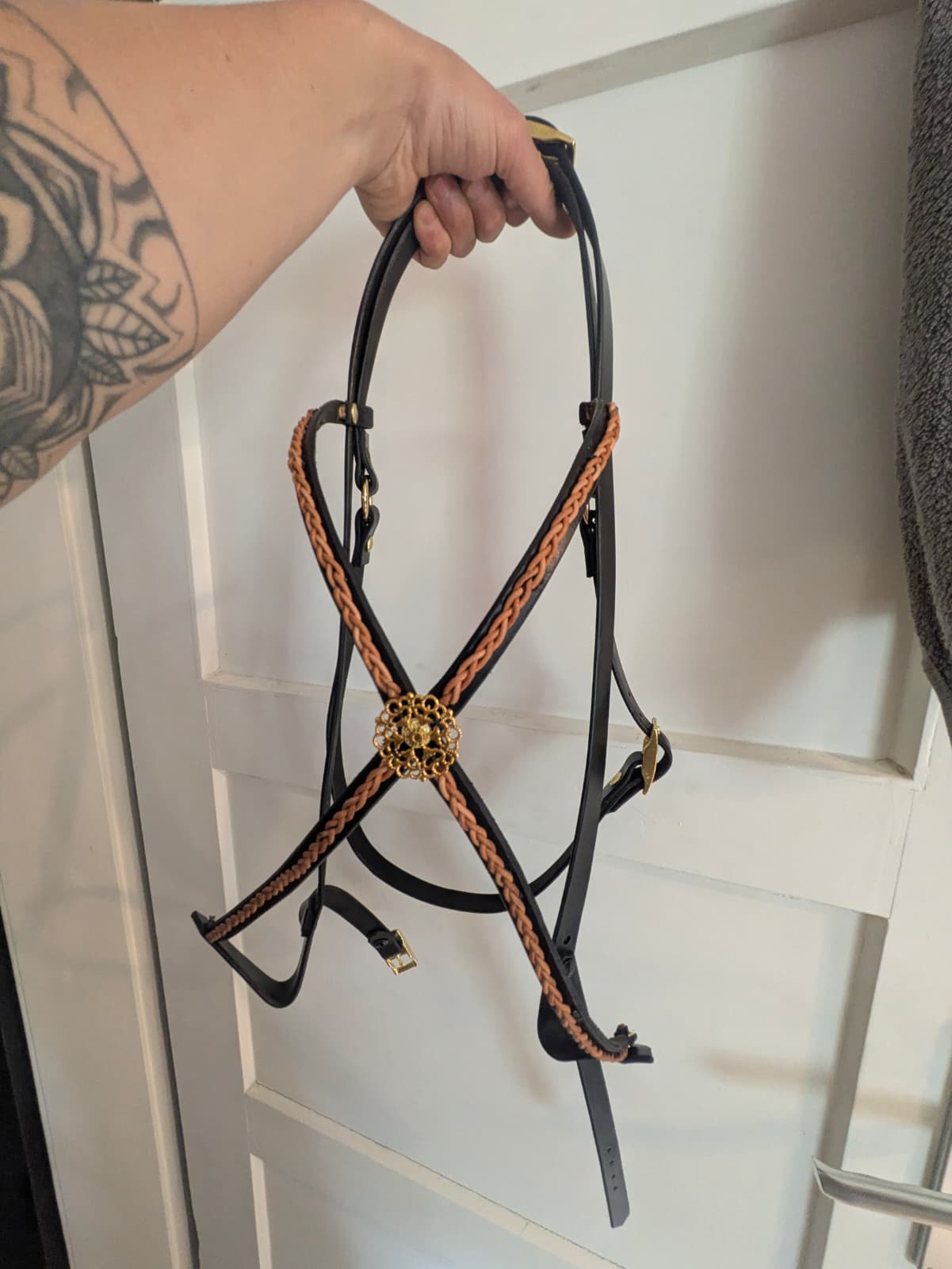 Handgefertigter Zaum aus schwarzem Leder mit geflochtenem Stirnband und goldener Zierrosette